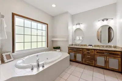 The large ensuite bathroom features double vanities, relaxing jacuzzi, and a large shower ready for use.