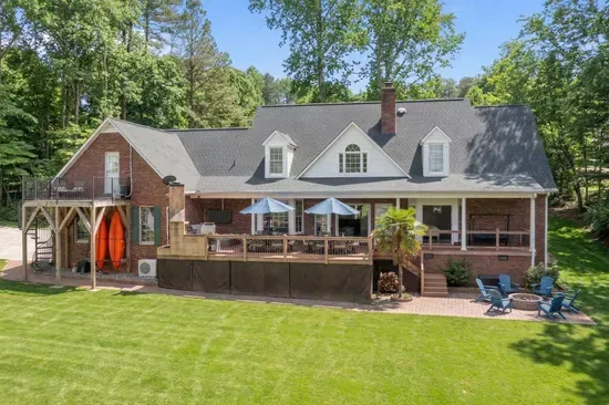 The rear view of the home showcases its expansive deck, large windows, and inviting outdoor spaces, perfectly blending comfort and natural beauty.