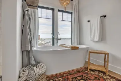 Large soaking tub ensuite in primary bedroom with views of the lake
