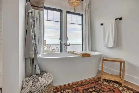 Large soaking tub ensuite in primary bedroom with views of the lake
