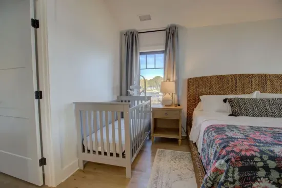 Primary bedroom located off the main living area. King size bed, Sony HDTV, direct porch access, and a crib and rocking chair.