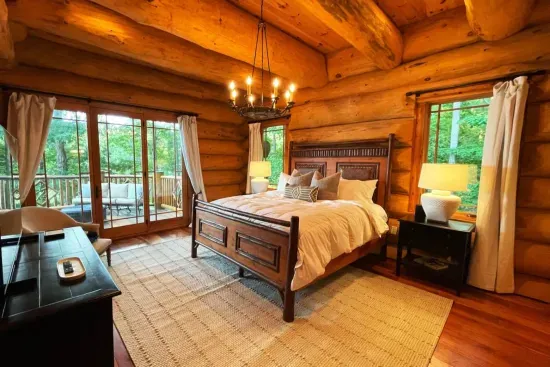 This inviting primary suite blends rustic elegance with comfort, complete with a plush king bed, thoughtful lighting, and direct access to your own private deck with fresh air and quiet surroundings.