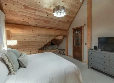 This inviting guest bedroom features a plush king bed, vaulted wood ceilings, and warm natural finishes, creating a peaceful retreat with plenty of space to relax and unwind.