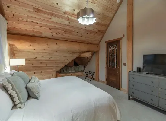 This inviting guest bedroom features a plush king bed, vaulted wood ceilings, and warm natural finishes, creating a peaceful retreat with plenty of space to relax and unwind.