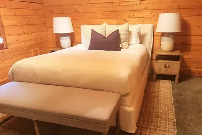 This inviting guest bedroom features a plush queen bed, vaulted wood ceilings, and warm natural finishes, creating a peaceful retreat with plenty of space to relax and unwind.