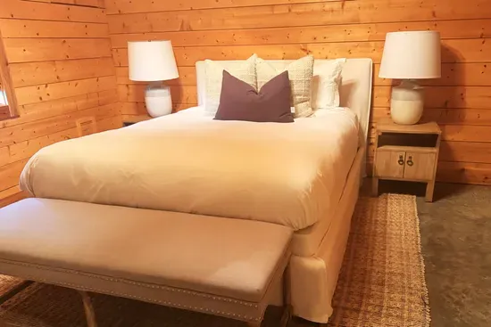 This inviting guest bedroom features a plush queen bed, vaulted wood ceilings, and warm natural finishes, creating a peaceful retreat with plenty of space to relax and unwind.