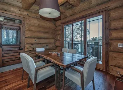 This inviting dining area pairs rustic log walls with modern comfort, offering a beautiful wood table and direct access to the deck—perfect for leisurely breakfasts and relaxed dinners.