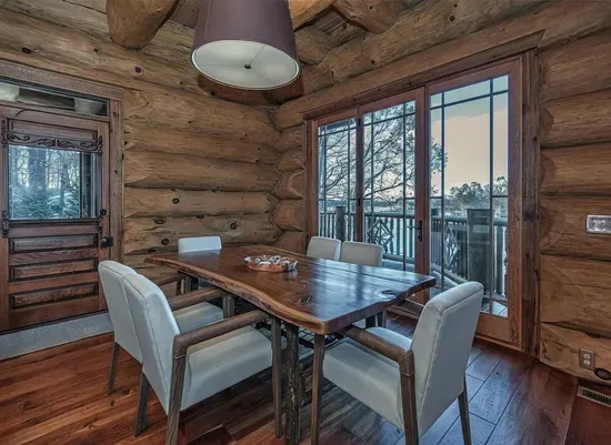 This inviting dining area pairs rustic log walls with modern comfort, offering a beautiful wood table and direct access to the deck—perfect for leisurely breakfasts and relaxed dinners.
