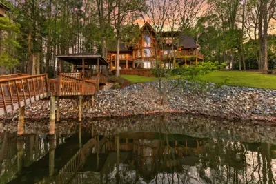 This stunning rear view showcases the home’s multi-level design, lakeside decks, and private dock—offering a resort-style experience tucked into a peaceful wooded setting.