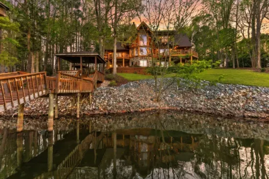 This stunning rear view showcases the home’s multi-level design, lakeside decks, and private dock—offering a resort-style experience tucked into a peaceful wooded setting.
