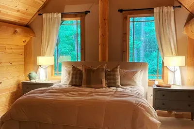 This inviting guest bedroom features a plush king bed, vaulted wood ceilings, and warm natural finishes, creating a peaceful retreat with plenty of space to relax and unwind.