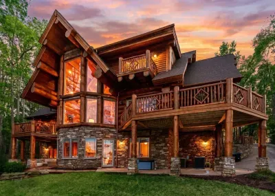 Multiple decks and gathering spaces make this luxury log cabin ideal for groups, offering privacy, comfort, and beautiful views from every level as the home glows in the evening light.