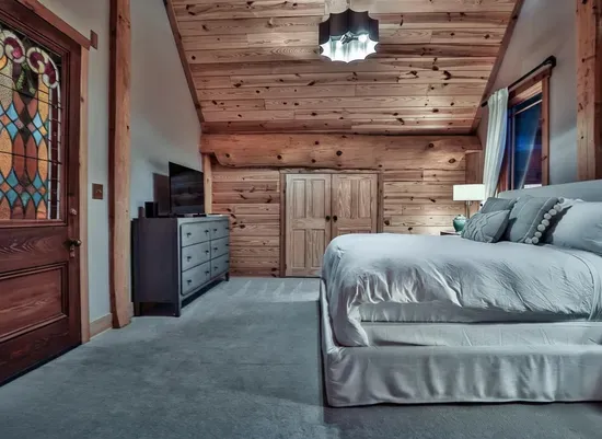 This inviting guest bedroom features a plush king bed, vaulted wood ceilings, and warm natural finishes, creating a peaceful retreat with plenty of space to relax and unwind.