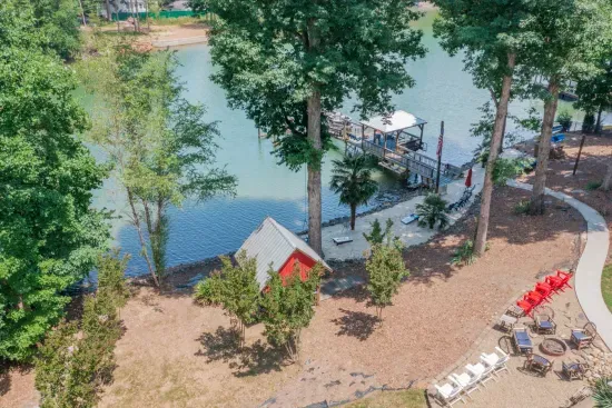 Aerial view of the property with hot tub (under shed roof), firepit, private dock, and sand beach.