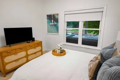 Adjacent to the living room is a well-appointed bedroom with queen bed, TV, and has direct access to a shared bathroom.