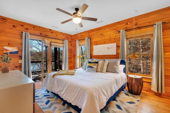 Rest comfortably on our premium king-size mattress in the upstairs primary bedroom with exposed wood walls and lake view.