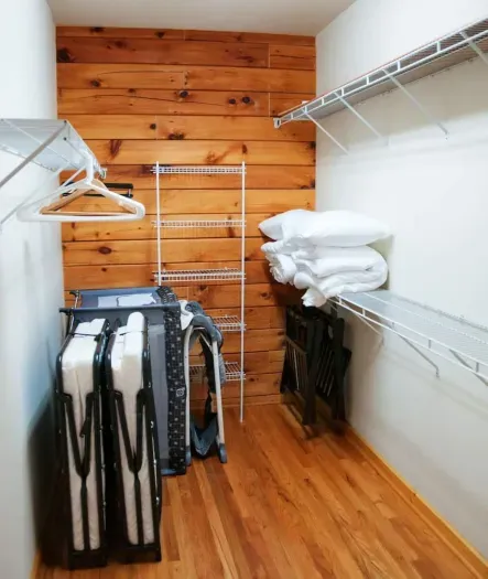 Upstairs large primary closet with two folded twin foam mattresses (and associated sheets, pillows, duvets), playpen, folded high chair and two luggage racks.