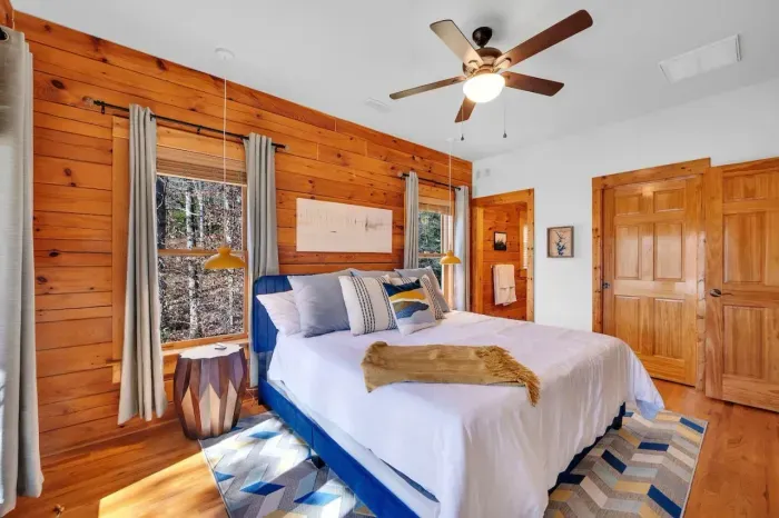 Upstairs primary bedroom with bare wood walls and king size bed.