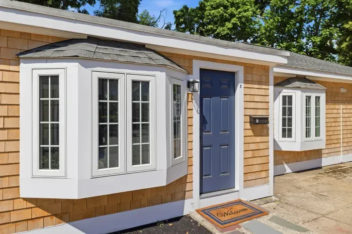 Charming cottage entry with bay windows and a bold blue front door