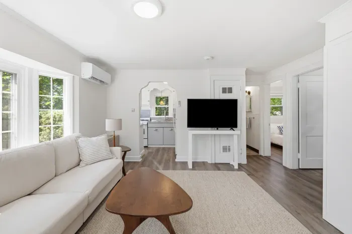 Bright, modern lounge with large windows, TV, and easy kitchen access