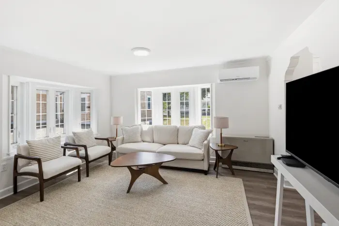 Living room area, with big windows, Ac unit, cozy seating, and large TV