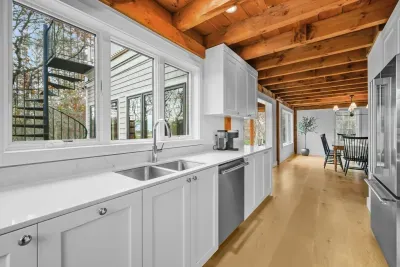 Bright modern kitchen with rustic beams, big windows, and dining nook