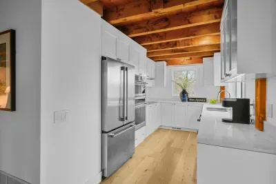 Bright designer kitchen with exposed wood beams and stainless appliances
