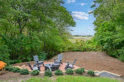 Secluded fire pit patio with Adirondack chairs and peaceful water views