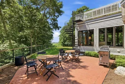Private tree-lined patio with grill, dining seating, and elevated deck access