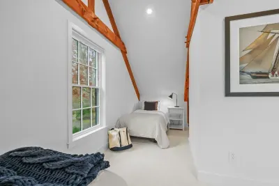 Cozy loft bedroom with vaulted ceilings, exposed beams, and natural light