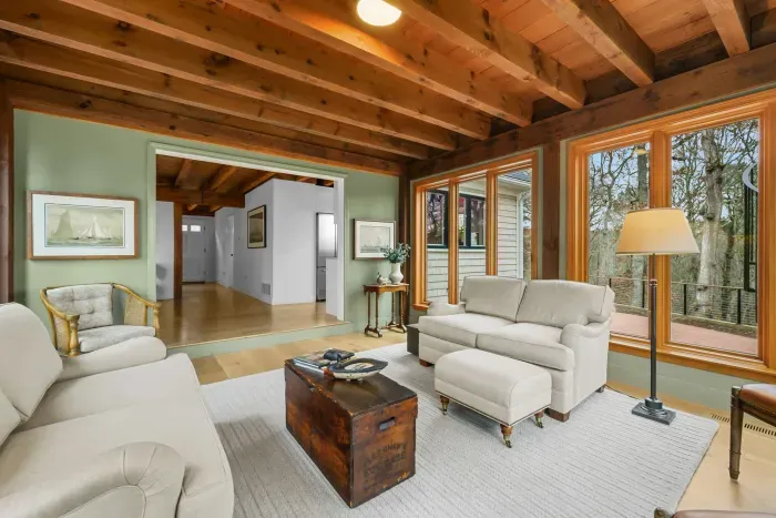 Cozy wood-beam lounge with large windows and serene wooded views