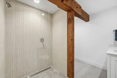 Spacious walk-in shower with rustic wood beams and modern finishes