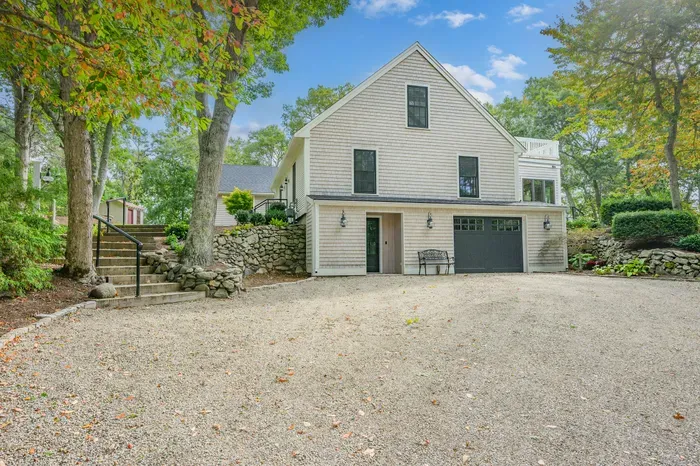 Charming cottage exterior with spacious drive, garage, and wooded privacy