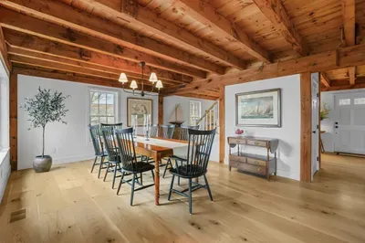 Rustic beam-lined dining room with spacious seating and warm natural light