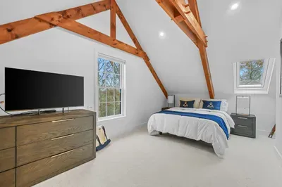 Bright loft bedroom with exposed beams, TV, and peaceful natural light