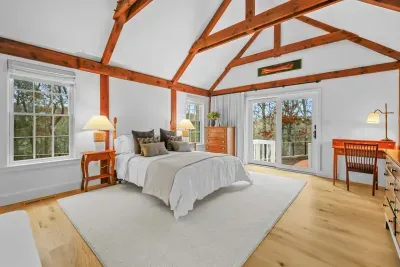 Vaulted-beam bedroom with deck access and serene woodland views