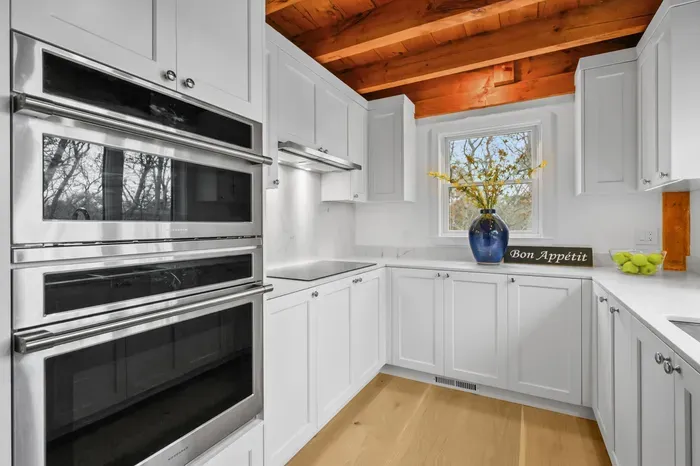 Bright designer kitchen with double ovens and warm wood beam ceiling