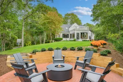 Private backyard with fire pit, lush lawn, and scenic wooded setting