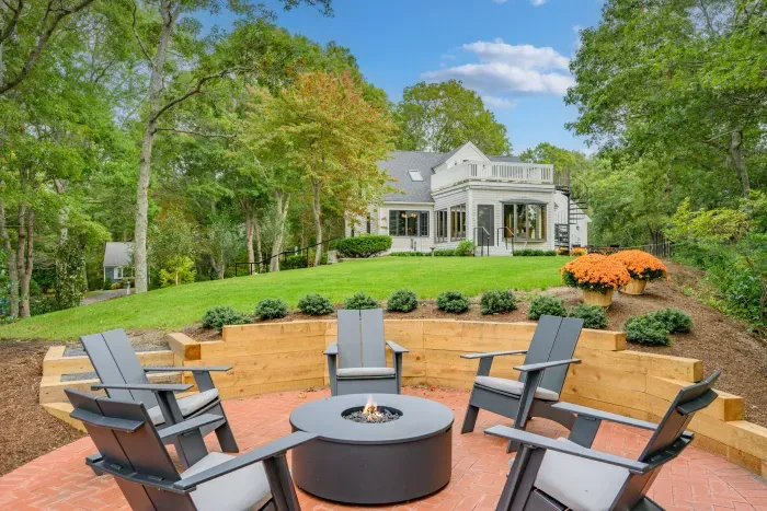 Private backyard with fire pit, lush lawn, and scenic wooded setting