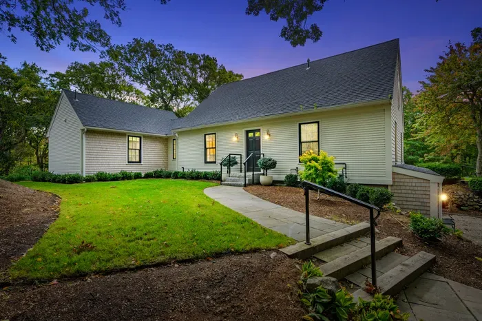 Charming wooded retreat with glowing entry and lush front lawn