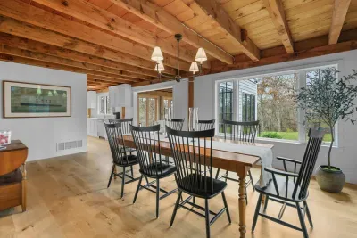 Bright dining room with exposed beams, big windows, and rustic charm