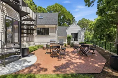Private brick patio with outdoor seating surrounded by mature trees