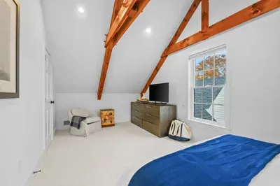 Bright loft-style bedroom with exposed beams and cozy seating