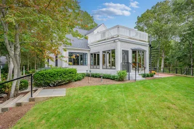 Peaceful tree-lined home with manicured lawn and spacious rooftop deck
