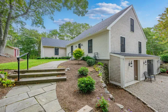 Charming Cape home with landscaped entry, garage, and peaceful wooded setting