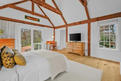 Airy vaulted bedroom with exposed beams and private deck access