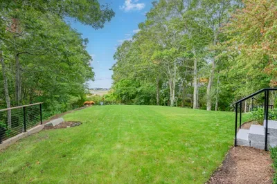 Private, tree-lined backyard with a spacious lawn and peaceful views