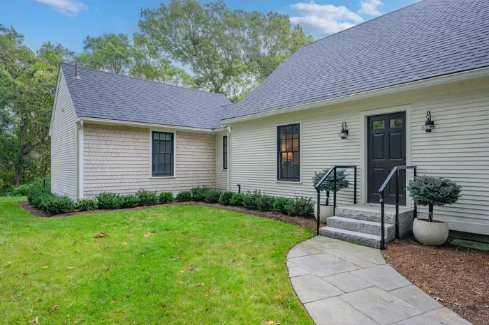 Charming private entry with landscaped lawn and peaceful wooded setting