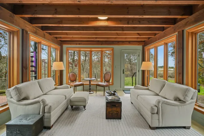 Sun-filled lounge with panoramic windows and warm rustic beams