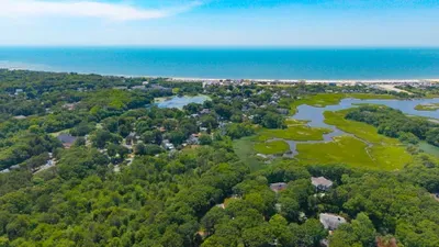 Peaceful coastal setting with beach views, marshlands, and lush greenery